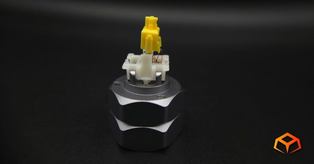 Macro shot of a Gateron Milky Yellow Pro V3 switch without the top housing with the stem, spring, and leaf visible